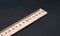 Fifteen cm. Regular size. Wooden ruler on a black background. Ruler Simple. School board background