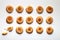 Fifteen handmade cookies with apricot jam arranged in even rows on white background. One in the corner is broken