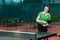Fifteen year old beautiful Caucasian teen girl in green sports t-shirt makes a serve in table tennis