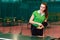 Fifteen year old beautiful Caucasian teen girl in green sports t-shirt throws the ball in table tennis