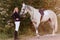 Fifteen-year-old teenage girl in black boots and thoroughbred white horse