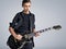 Fifteen years old guitarist with a black electric guitar. Teenage musician holds guitar