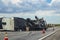 Fifth wheel Recreational Vehicle overturned on a highway with the underside torn up and things spilling out into the roadway after