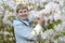 The fifty-year-old woman against the background of the blossoming Shlippenbakh`s rhododendron