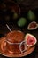 Fig jam in a glass jar on a copper Turkish platter, half a fresh fig next to it and fruit in the background. close-up, preparation