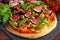 Fig pizza with bacon, green pimiento olives, rocket and basil leaves