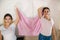 Fight against breast cancer. Two excited women of various ages wearing pink ribbons holding a pink flag