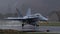 Fighter plane takes off in the rain raising splashes of water with reflections