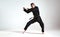 Fighting man in black kimono fighter shows karate technique on studio background with copy space, mix fight concept
