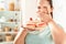 Fighting Temptation. Chubby girl standing in kitchen holding plate with desserts scared close-up