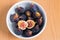 Figs fruits in a bowl on wooden background, top view