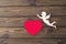 The figure of an angel, the figure of a red heart on a wooden background.