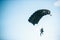 Figure of a parachutist with a black parachute against a blue sky