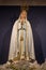 Figure of Saint Mary with Crown in cathedral. Our Lady in white. Praying Madonna sculpture with white flowers.