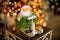 Figure of santa claus on sleigh with green plant stands on table against blurred background