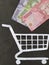 figure of a shopping cart on white paper and Chilean money