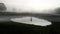 A figure standing reflected in a pond, silhouetted on a spooky foggy winters evening in the countryside