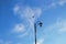 A figured lantern and a flying bird silhouetted against a blue sky with clouds. Urban poetry