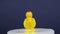 Figures of bright yellow chickens made of plastic are spinning on a dark background, the idea of a design concept
