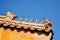 Figures guard the top of an orange tiled traditional rooftop in China.