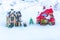 The figures of people standing in the snow between the two houses and a small New Year tree.