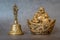 Figurine Cheerful Hotei  and golden bell close-up, soothing and meditative. Smiling Buddha and golden bell Isolated on gray