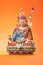 Figurine of Padmasambhava on an orange background.