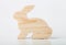 A figurine of a rabbit or a hare carved from solid pine by a hand jigsaw. On a white background