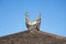 Figurine of a rooster on a tree stump on a background of blue sk