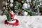 Figurine of santa claus on white fur blanket, against background of burning garland of christmas tree