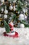 Figurine of santa claus on white fur blanket, against background of burning garland of christmas tree. New Year or Christmas greet