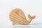 A figurine of a whale carved from solid pine by a hand jigsaw. On a white background