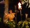 Fijian warrior lighting tiki torch at sunset