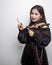 Filipina in a vampire costume pointing to the side with index fingers on white background