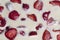 Filled frame background wallpaper shot of strawberries on the surface of a milky white vanilla cheese cake cream liquid