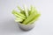 filled frame  shot of a brown beige bowl filled with crunchy juicy green celery sticks on a white background