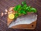 Fillet of raw codfish on a wooden surface with garlic and greens