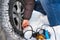 Filling air into a car tire. Winter. Closeup of a repairing a flat tire use compressor