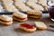 Filling Christmas cookies with red strawberry jam