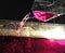 Filling a fish tank with pink water using a plastic bottle in a dim lightning