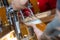 Filling glass with beer. Bartender hand at beer tap pouring draught beer in glass serving in restaurant or pub. Close-up