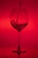 Filling the glass, pouring wineglass on red background