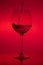 Filling the glass, pouring wineglass on red background