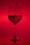 Filling the glass, pouring wineglass on red background