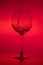 Filling the glass, pouring wineglass on red background