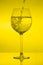 Filling wine glass on yellow background, pouring wineglass