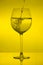 Filling wine glass on yellow background, pouring wineglass