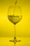 Filling wine glass on yellow background, pouring wineglass