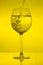 Filling wine glass on yellow background, pouring wineglass