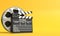 Film reel with clapperboard isolated on bright yellow background in pastel colors
